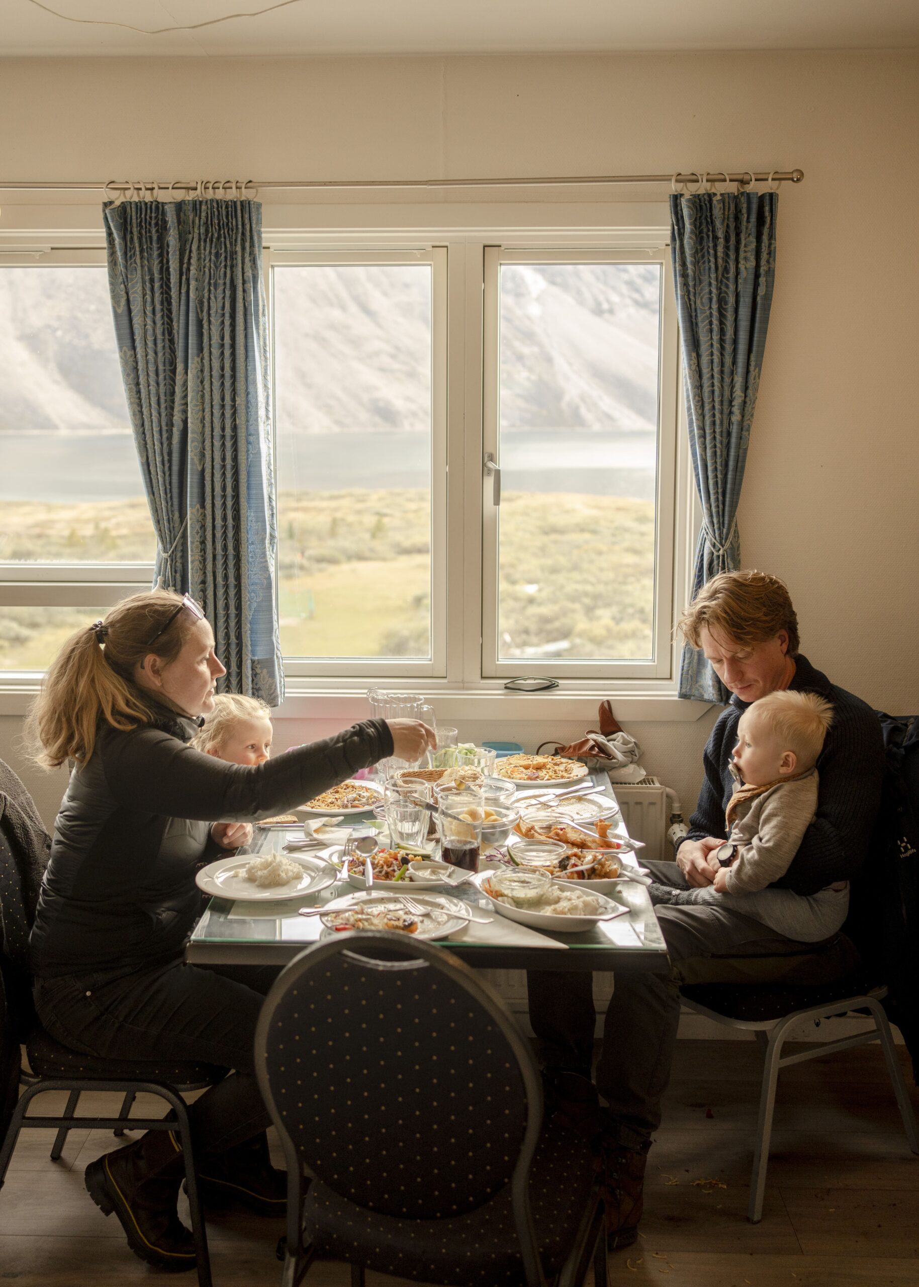 Familie nyder middagen sammen med udsigt til fjorden gennem panoramavinduer